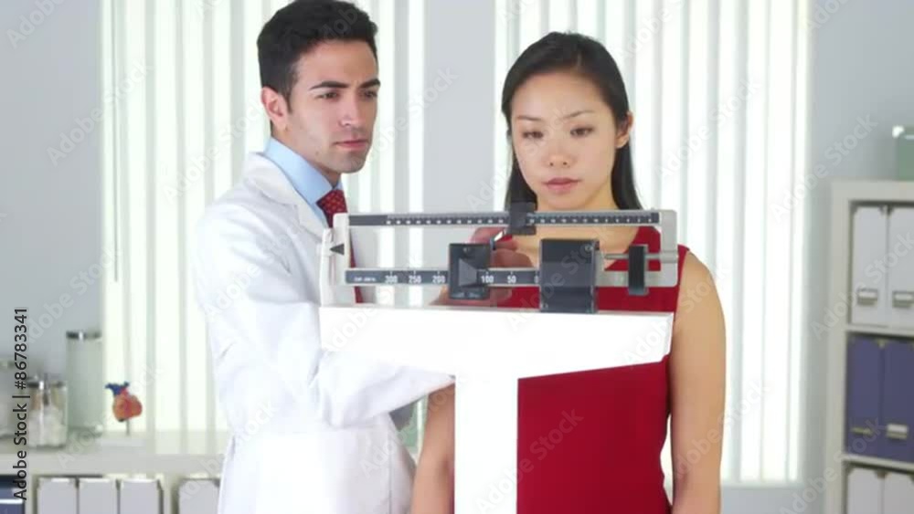 Happy Chinese patient being weighed on scales Happy Chinese patient being weighed on scales