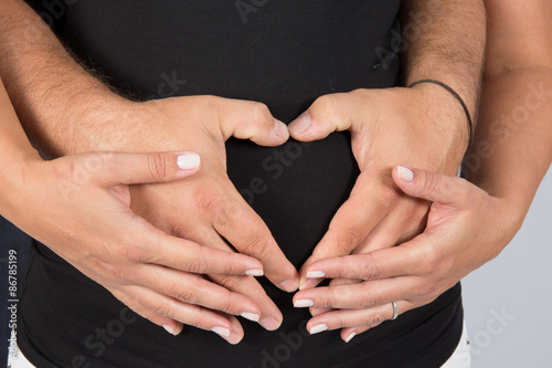 Close-up of a belly with the hands making a heart shape