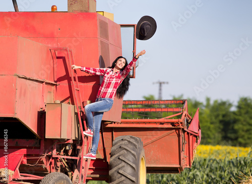 Woman throwing hat from combine harvester photo