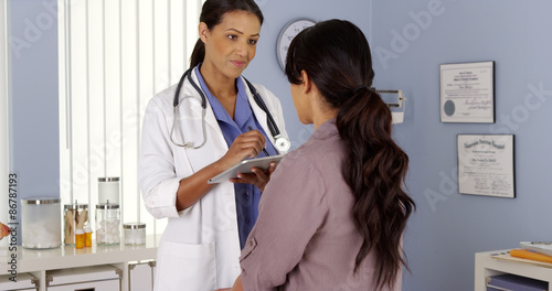 Black Primary Care Physician talking to female patient in Exam room photo