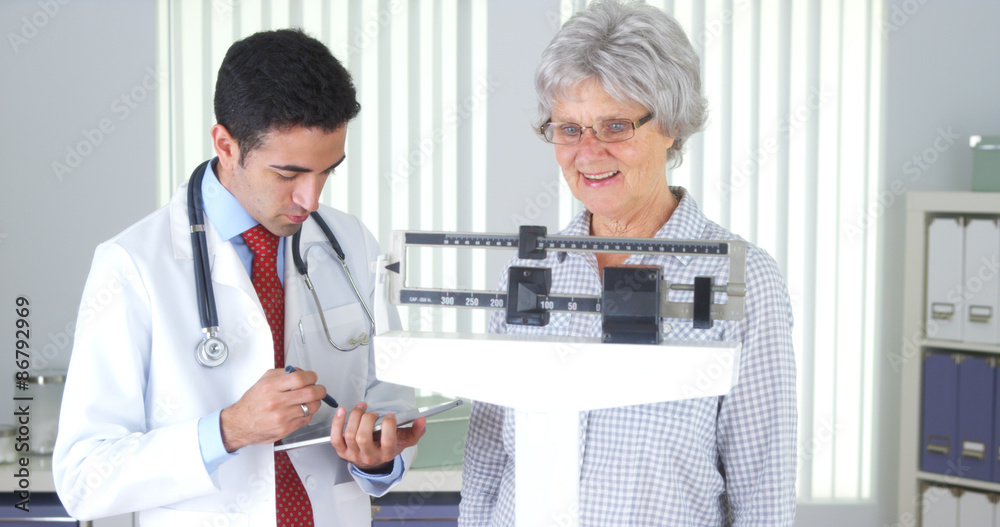 Fototapeta premium Mexican doctor weighing elderly patient