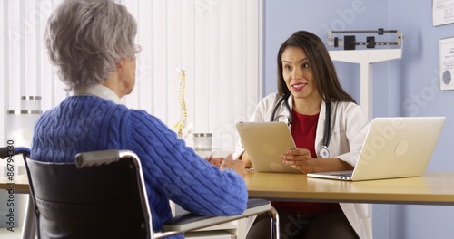 Young Mexican doctor talking with elderly patient