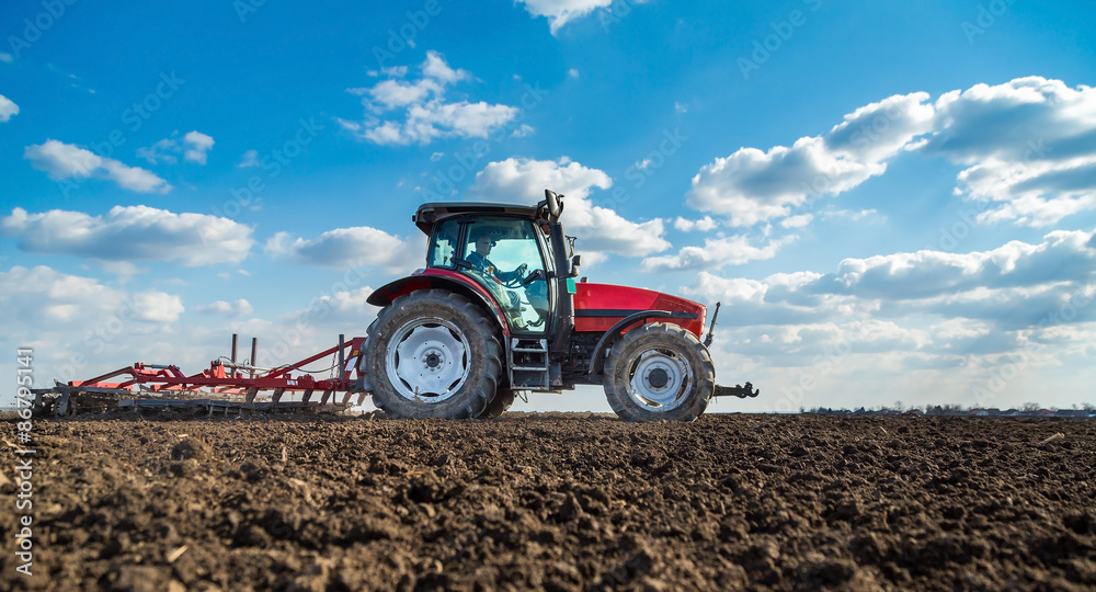 Naklejka premium Farmer in tractor preparing land with seedbed cultivator