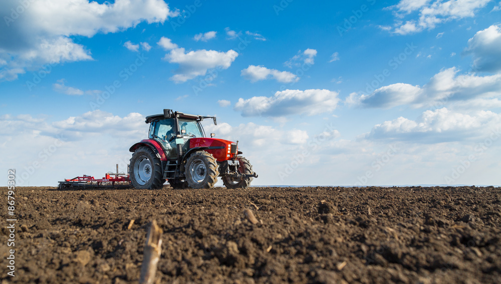Farmer in tractor preparing land with seedbed cultivator Farmer in tractor preparing land with seedbed cultivator