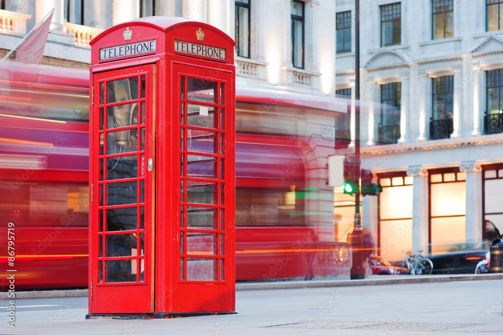 London, UK. Red telephone booth and red bus passing. Symbols of England.