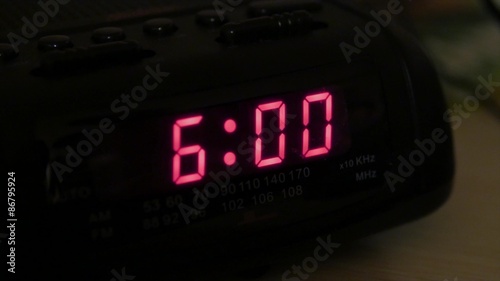 Man hits snooze on alarm clock photo