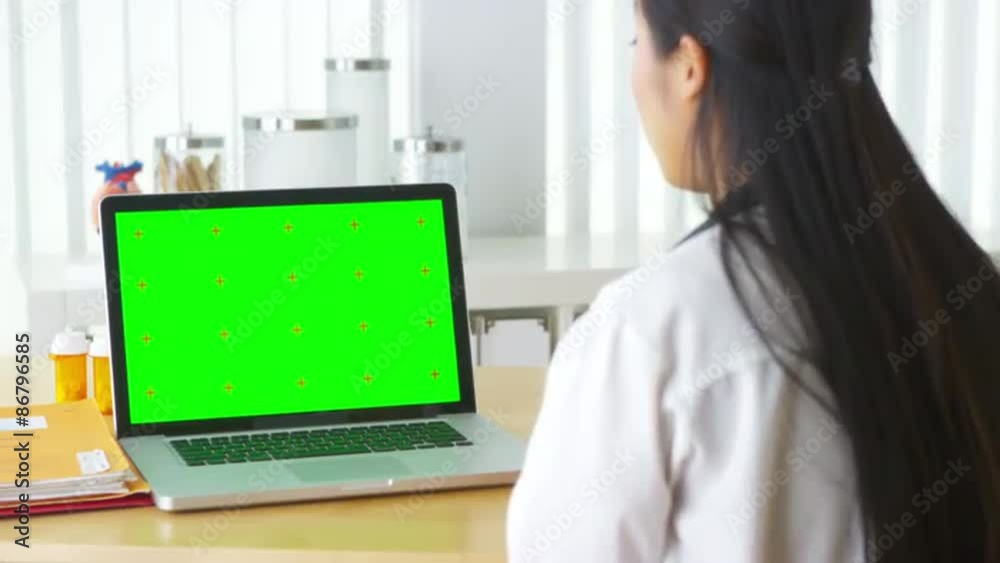 Chinese doctor talking to laptop with green screen Chinese doctor talking to laptop with green screen