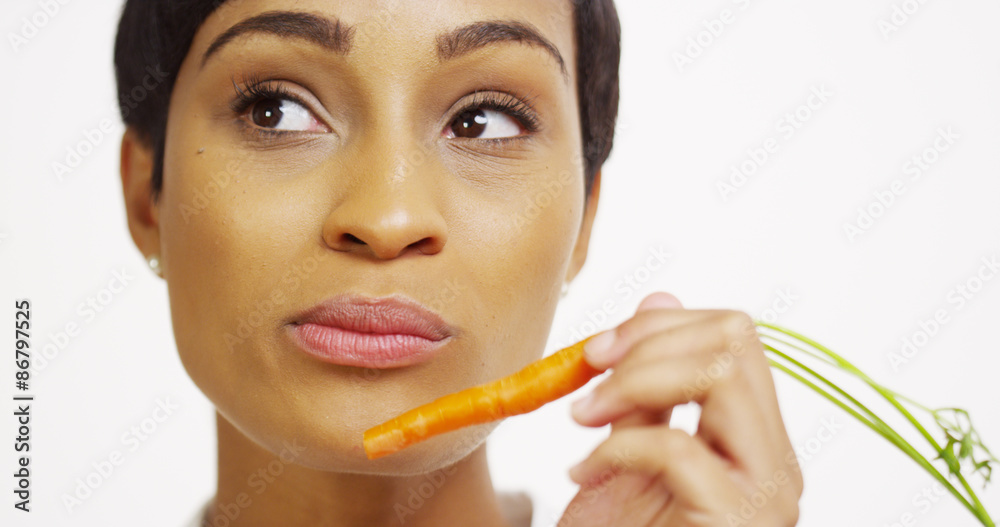 Close up of African woman eating carrot and smiling Close up of African woman eating carrot and smiling