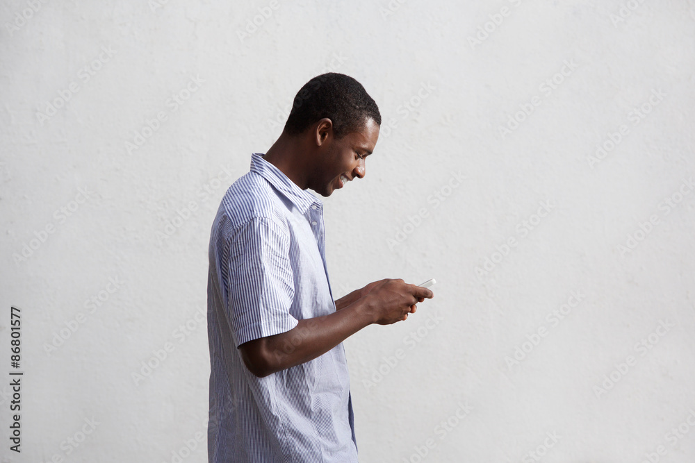 Smiling black guy walking and using mobile phone Smiling black guy walking and using mobile phone
