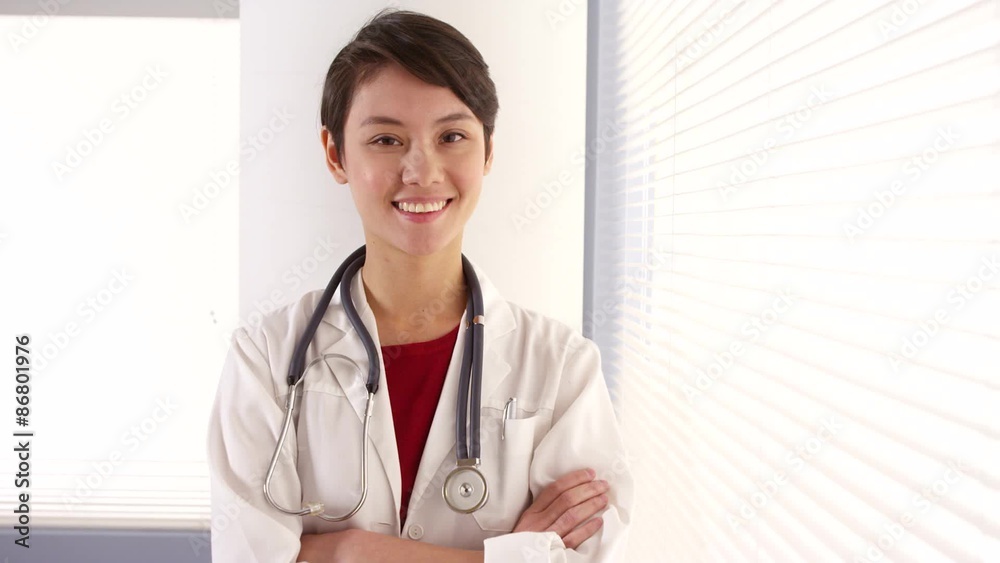 Confident Asian woman doctor standing by window Confident Asian woman doctor standing by window