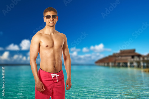 Man on beach with water bungalows