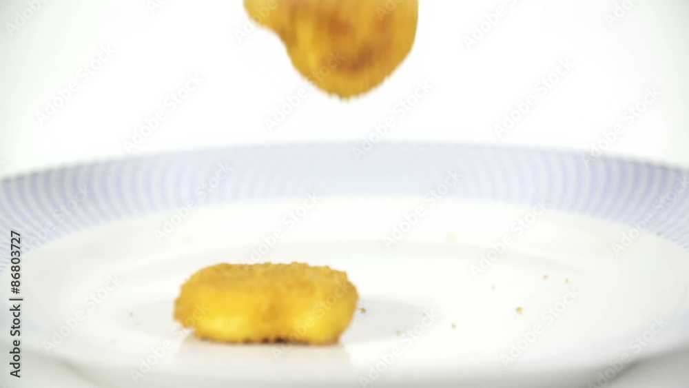 Chicken nuggets falling on plate in slowmotion Chicken nuggets falling on plate in slowmotion