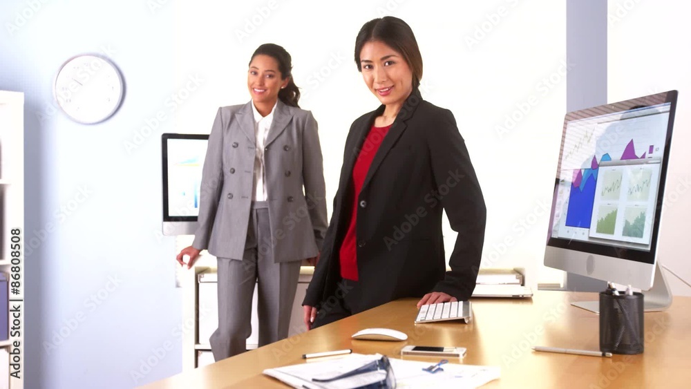Two multi-ethnic businesswomen smiling in office Two multi-ethnic businesswomen smiling in office