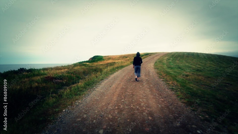Woman Walking on Road Above Coast Woman Walking on Road Above Coast