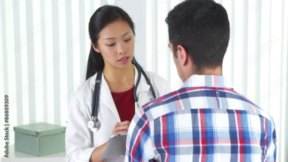 Asian doctor asking patient questions and taking notes Asian doctor asking patient questions and taking notes