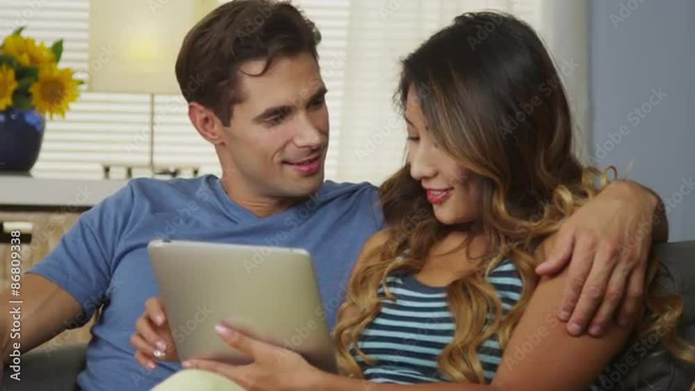 Happy mixed race couple laughing and smiling with tablet Happy mixed race couple laughing and smiling with tablet