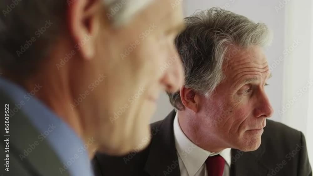 Senior businessmen standing by window talking Senior businessmen standing by window talking