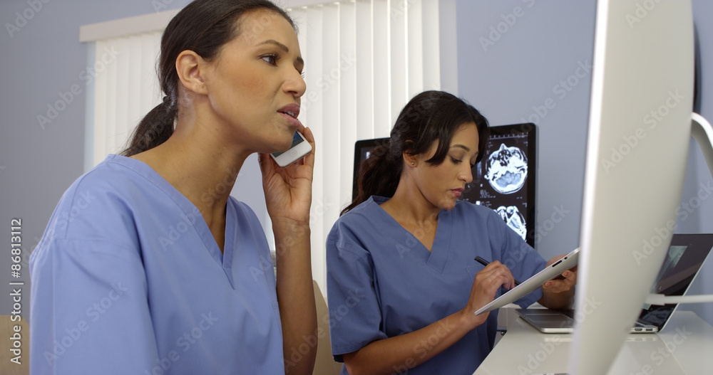 Two female medical personnel working as a team using modern technology Two female medical personnel working as a team using modern technology