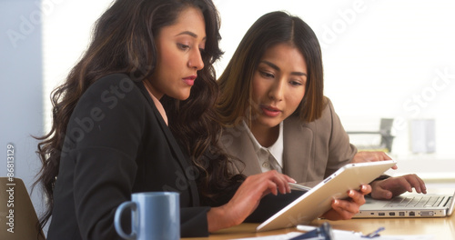 Mexican businesswoman sharing findings on tablet with Japanese colleague