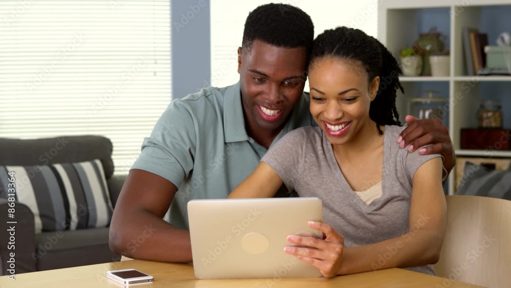 Happy young black couple using tablet computer together laughing Happy young black couple using tablet computer together laughing