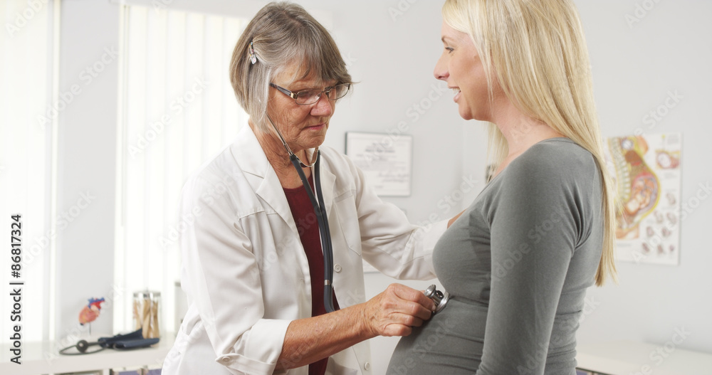 Fototapeta premium Doctor listening to pregnant woman's belly