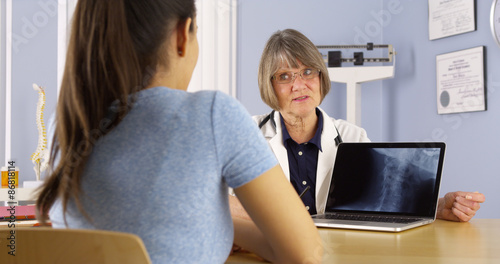 Senior doctor talking about xray to Hispanic woman patient