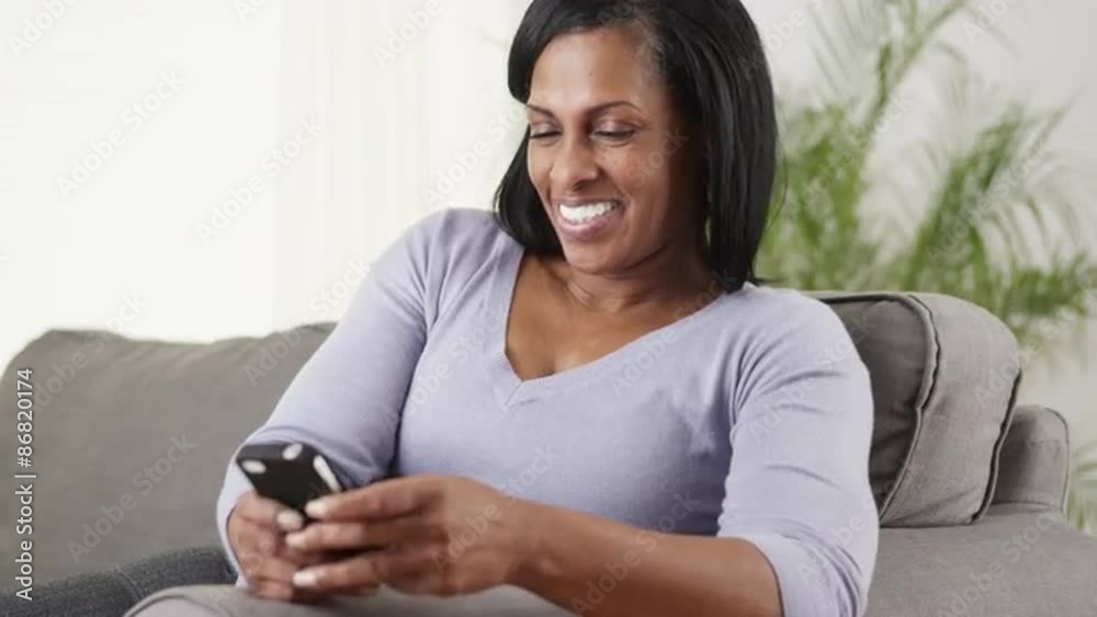Mature black woman texting smartphone laughing Mature black woman texting smartphone laughing