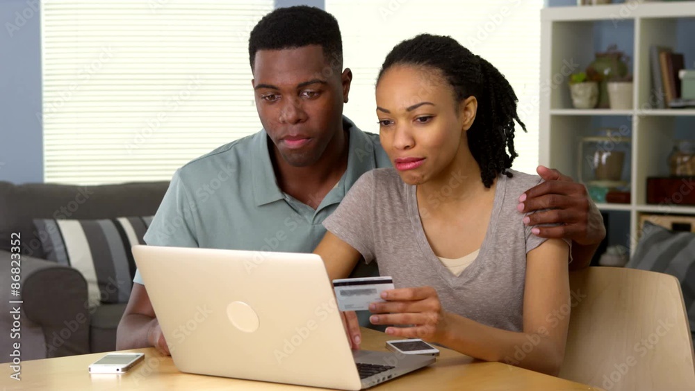 Smiling young black couple using credit card to make online purchase Smiling young black couple using credit card to make online purchase