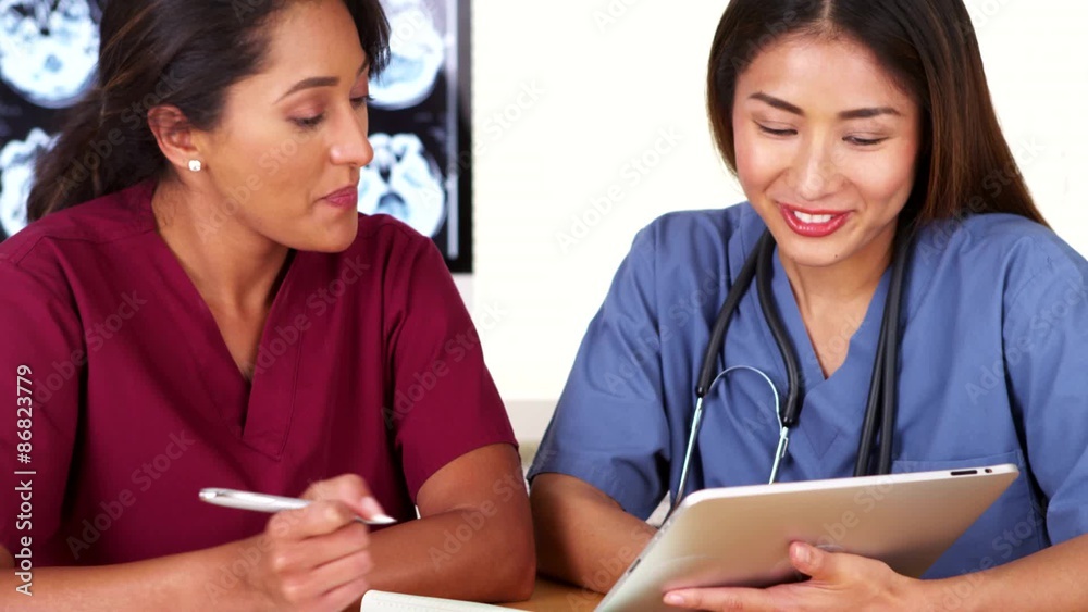 Diverse team of medical doctors working at desk with tablet Diverse team of medical doctors working at desk with tablet