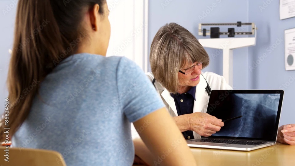 Senior doctor explaining neck x-ray to Mexican woman patient Senior doctor explaining neck x-ray to Mexican woman patient