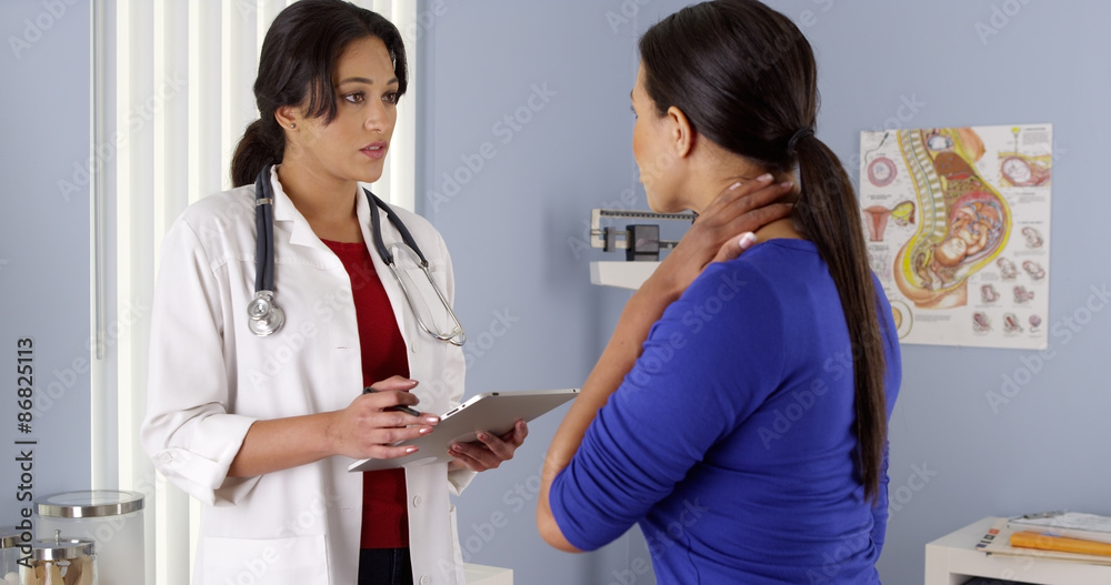 Fototapeta premium Hispanic OBGYN talking to african american patient with tablet