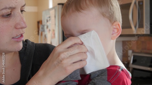 Little toddler blows nose into kleenex