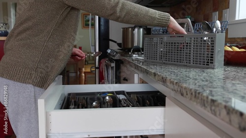 woman unloading a dishwasher utensils