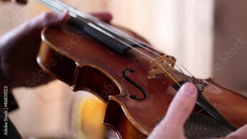 A cowboy blows straw off violin in an old barn photo