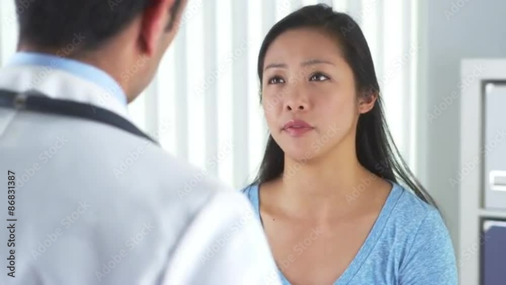 Asian patient describing wrist pain to doctor Asian patient describing wrist pain to doctor