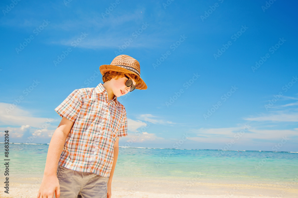 Happy kid boy in summer hat and hipster sunglasses walks at the