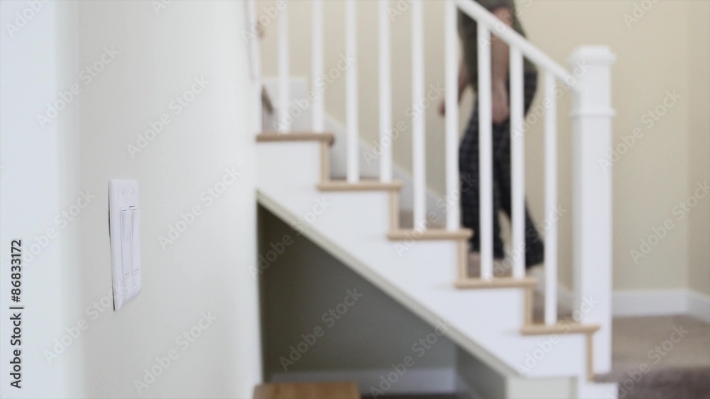 A man turns off light and walks up stairs