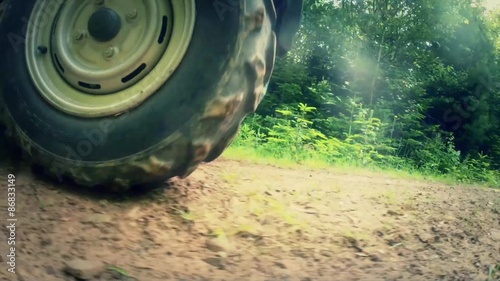 a low shot of a tire on four wheeler traveling on a dirt road
