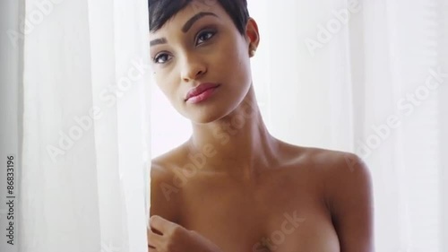 Sexy black woman standing by window with bare shoulders  photo