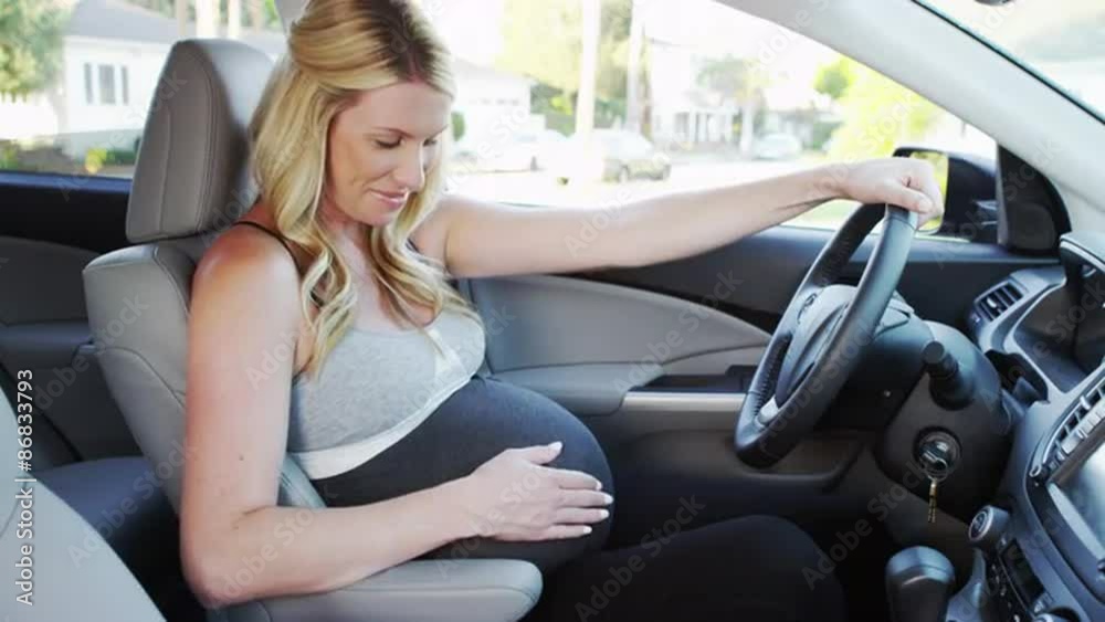 Beautiful pregnant woman sitting in car smiling Beautiful pregnant woman sitting in car smiling