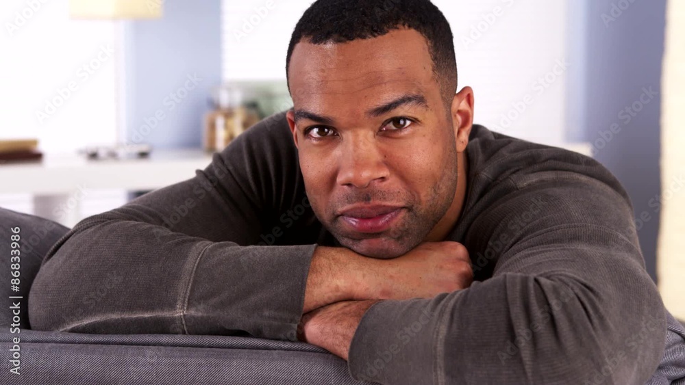 Smiling black man resting on couch Smiling black man resting on couch