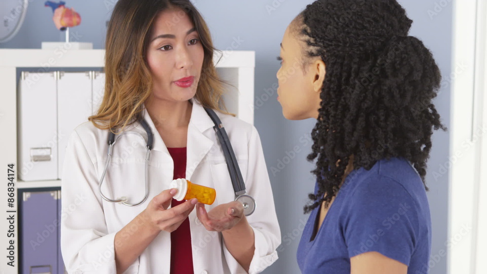Japanese physician explaining new prescription to African American patient Japanese physician explaining new prescription to African American patient