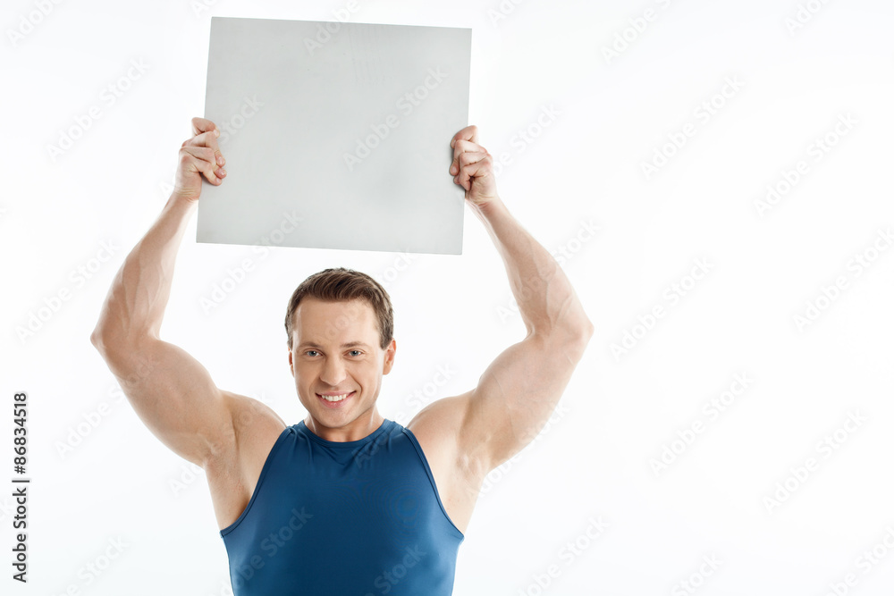Handsome sportsman is presenting white sheet of paper Handsome sportsman is presenting white sheet of paper