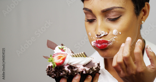 Black woman making a mess eating a huge fancy dessert