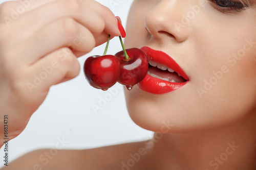 Beautiful young girl with red sweet cherry