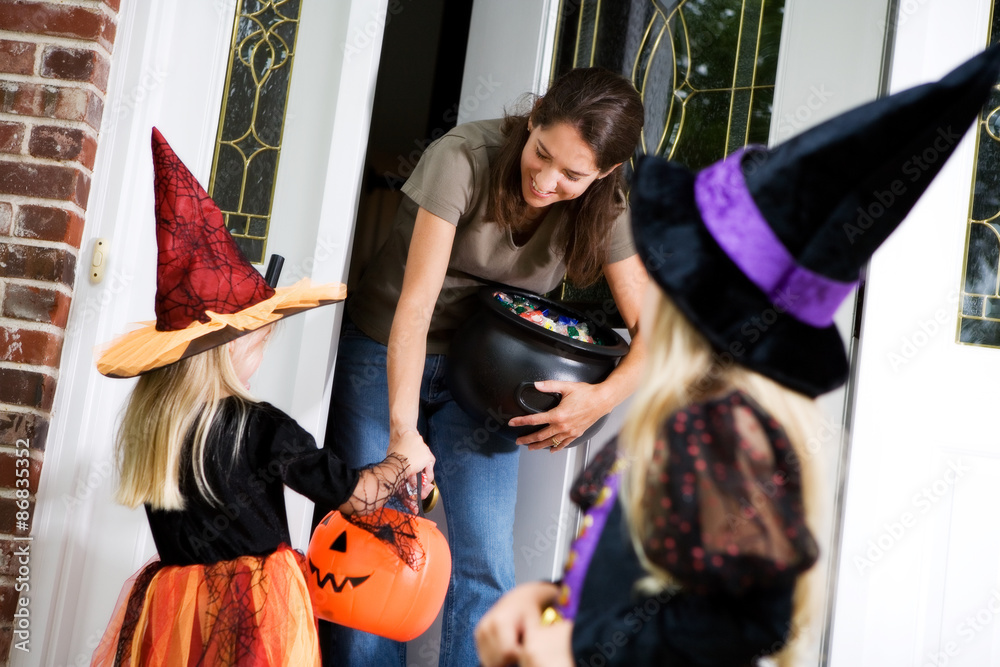 Fototapeta premium Halloween: Mother Hands Out Candy to Little Girl Witch