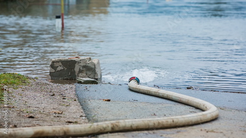 Fire hose pumping water in to flooded area photo