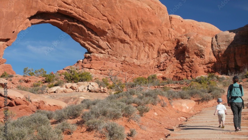 A family hiking at north window arch in Arches National Park