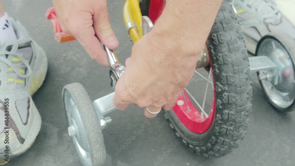 man puts training wheels on bike Stock Video Adobe Stock