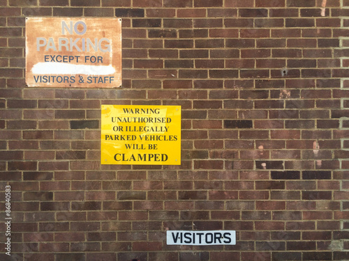 Parking warning signs on red brick wall